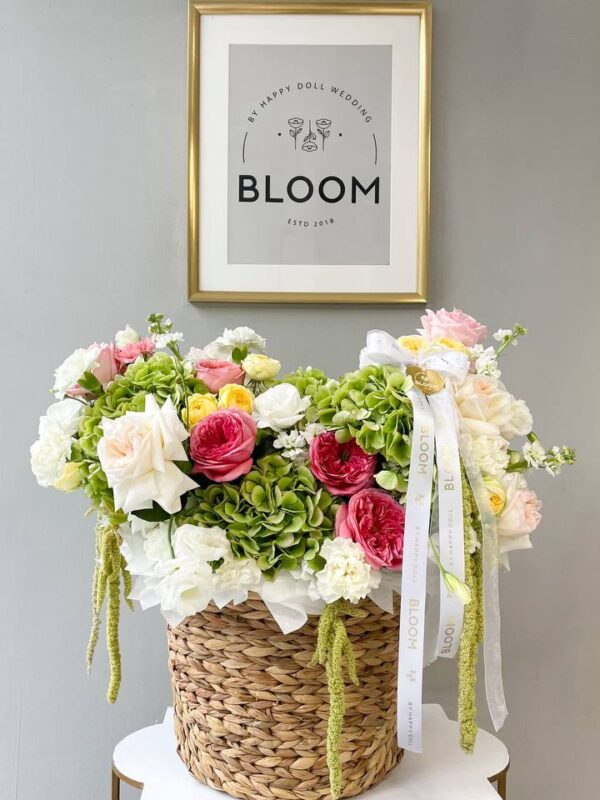 вторська квіткова композиція в плетеному кошику з трояндами, гортензією та сезонними квітами.