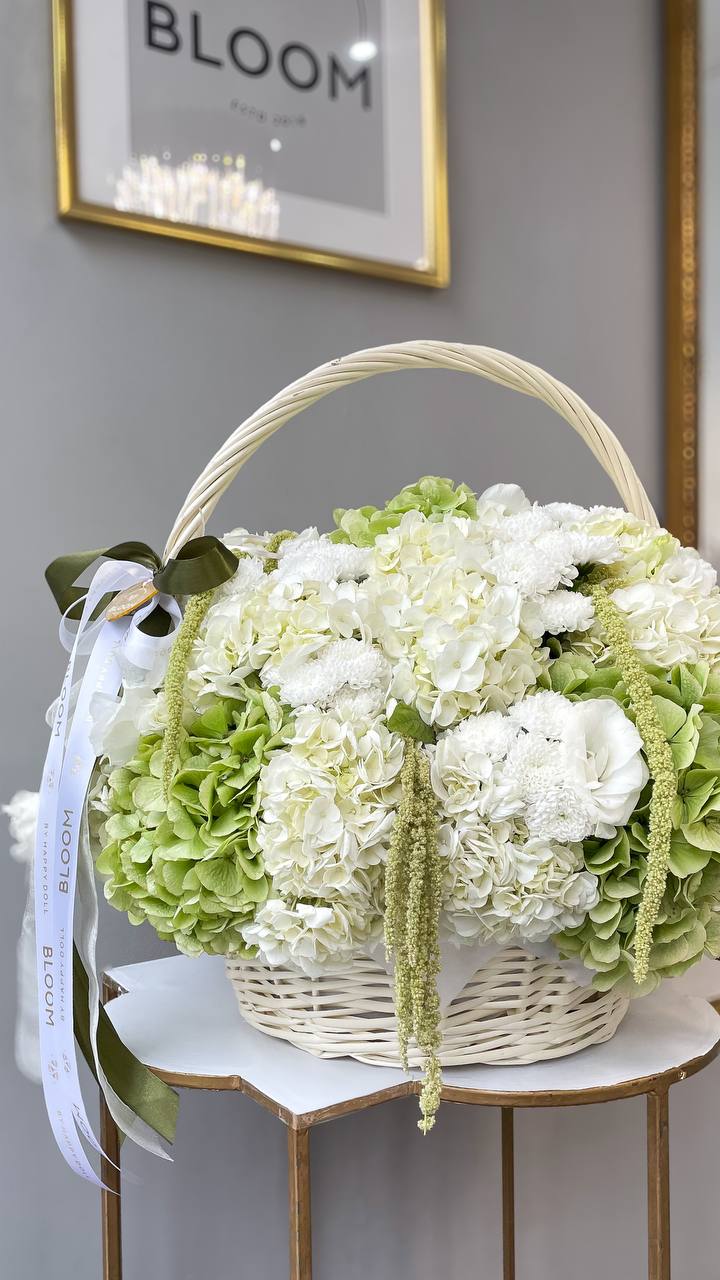 Квіткова композиція у кошику з гортензією та еустомою Квіткова композиція у білому кошику з білою та зеленою гортензією, еустомою і хризантемами від Bloom by Happy Doll