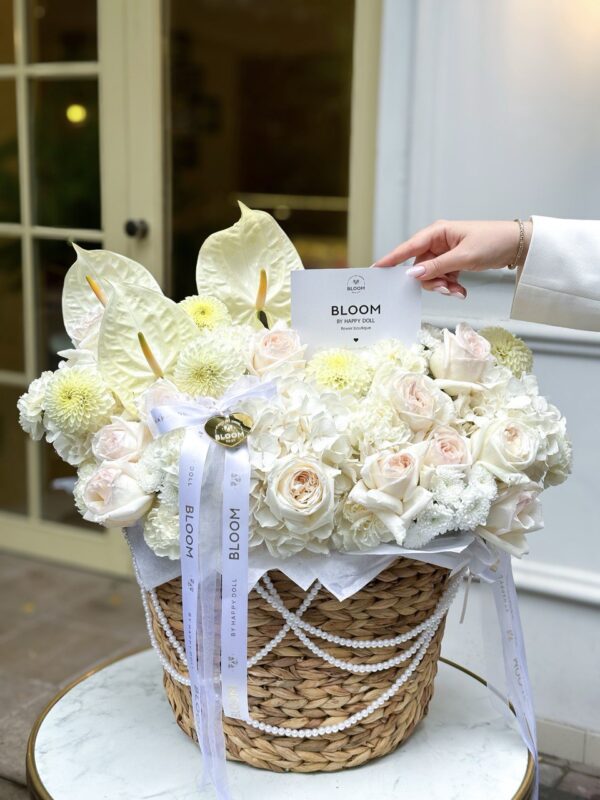 Композиція зі світлих квітів у декоративному кошику з перлинним декором.