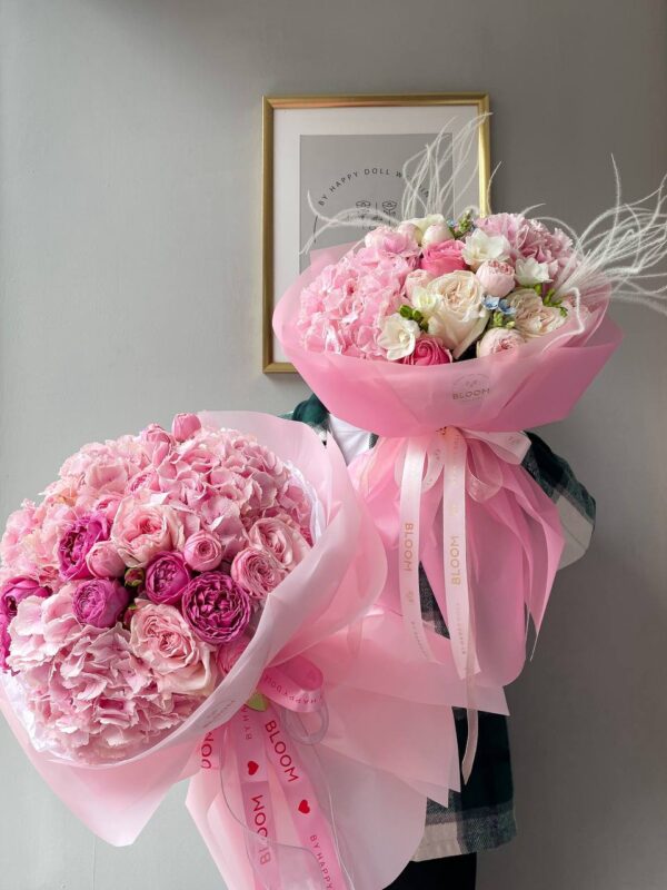 Два великі рожеві букети з півоніями, трояндами та гортензією, оформлені у рожеву плівку зі стрічками від Bloom by Happy Doll