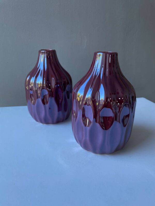 Дві керамічні вази винного кольору з глянцевою хвилястою поверхнею на світлому фоні
