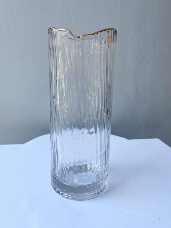 Прозора рифлена скляна ваза із золотим хвилястим краєм на світлому фоні