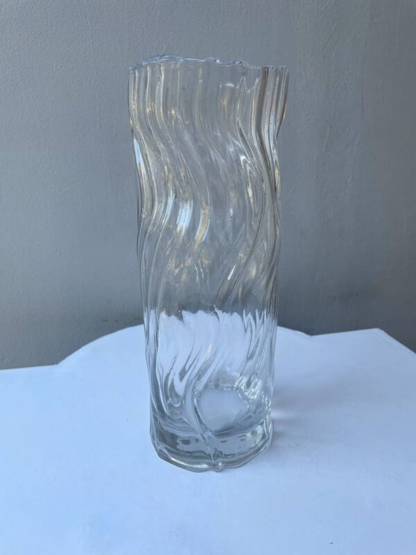Прозора хвиляста скляна ваза на світлому фоні