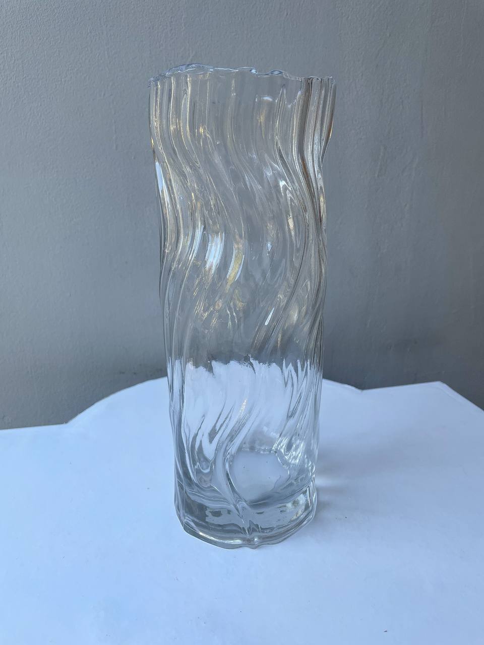 Ваза прозора рельєфна 25 см Прозора хвиляста скляна ваза на світлому фоні