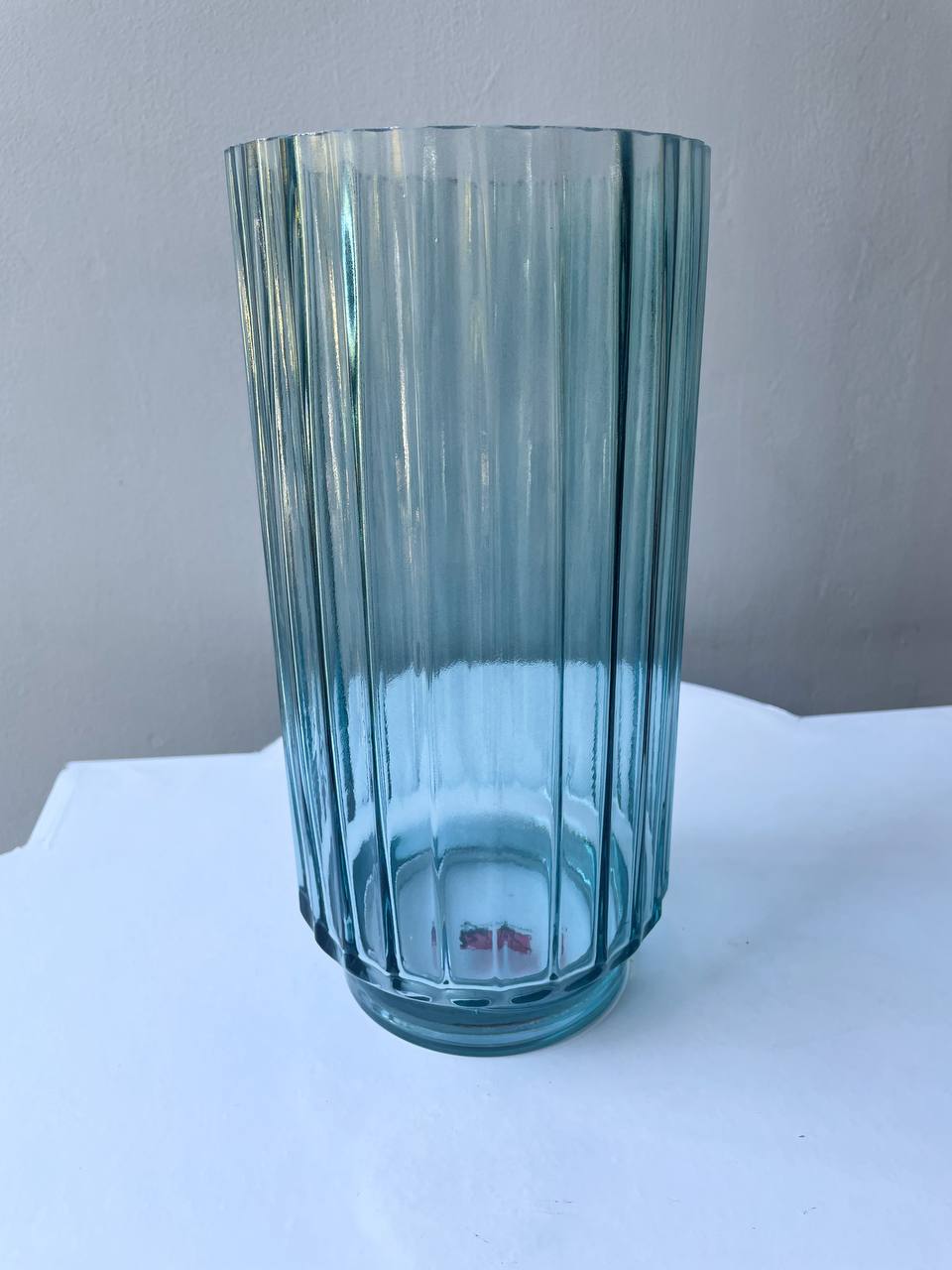 Ваза сіро-блакитна скло 25 см Сіро-блакитна рифлена скляна ваза на світлому фоні