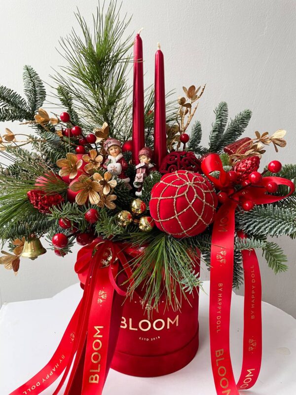 Різдвяна композиція Bloom у червоній коробці з хвойними гілками, свічками, іграшками та святковим декором в червоно-золотій гамі.
