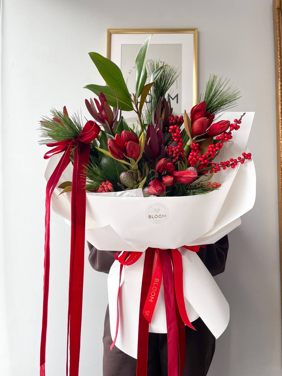 Christmas red magic / Різдвяна червона магія 2 Зимовий святковий букет із червоними квітами, декоративними ягодами та ялиновими гілками, оформлений у білий папір із червоними стрічками.