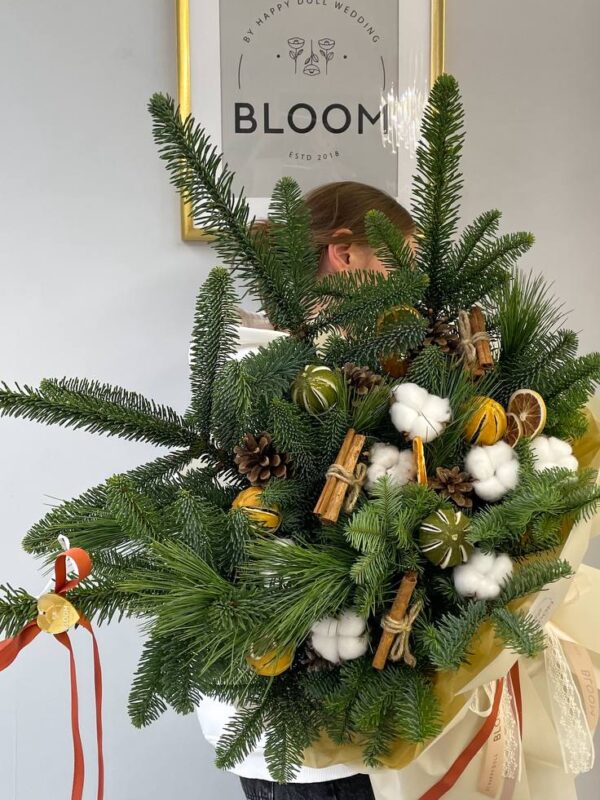 Зимова флористична композиція з хвої, кориці, шишок, бавовни та висушених цитрусів у святковому оформленні.