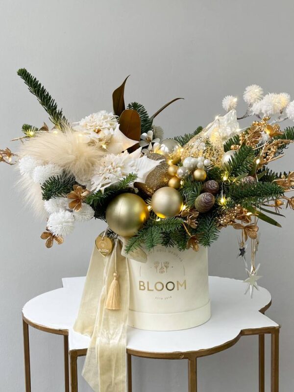 Зимова композиція у золотих та білих відтінках з хвоєю, кулями, квітами та святковим декором у коробці BLOOM.