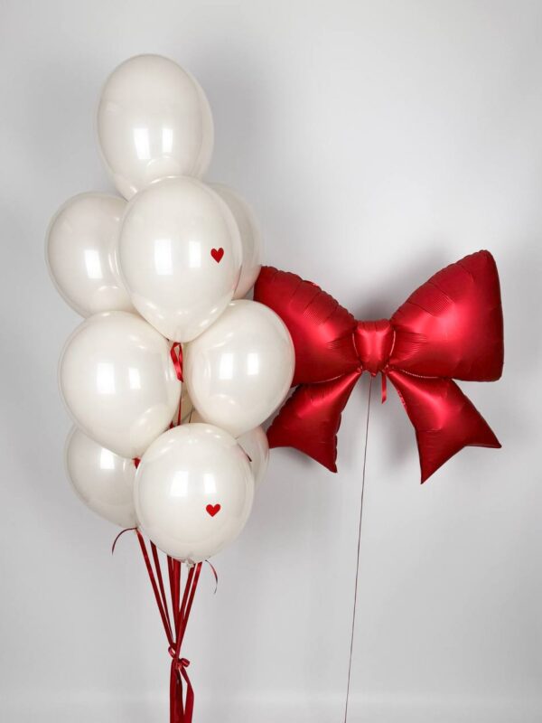 Повітряна композиція з білих кульок з червоними сердечками та фольгованим червоним бантом