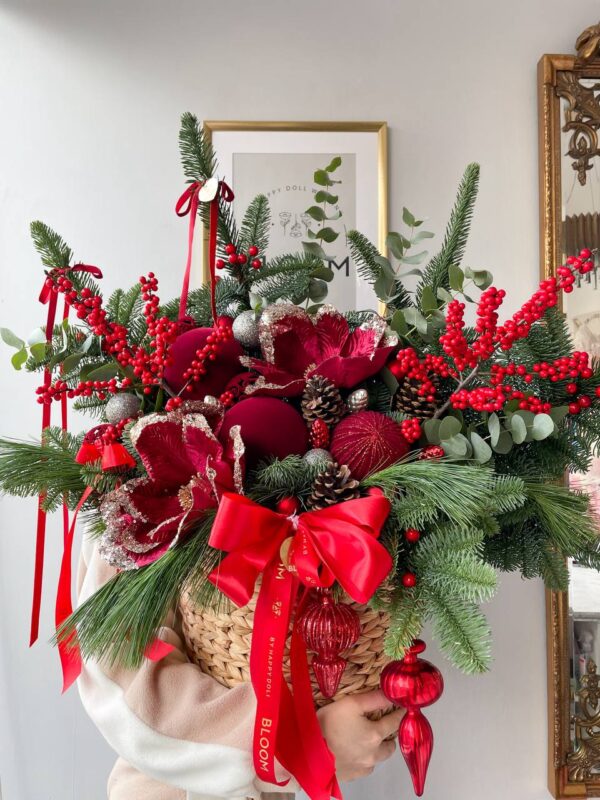 Новорічний кошик із хвоєю, червоними ягодами, декором та великим святковим бантом у червоному кольорі.