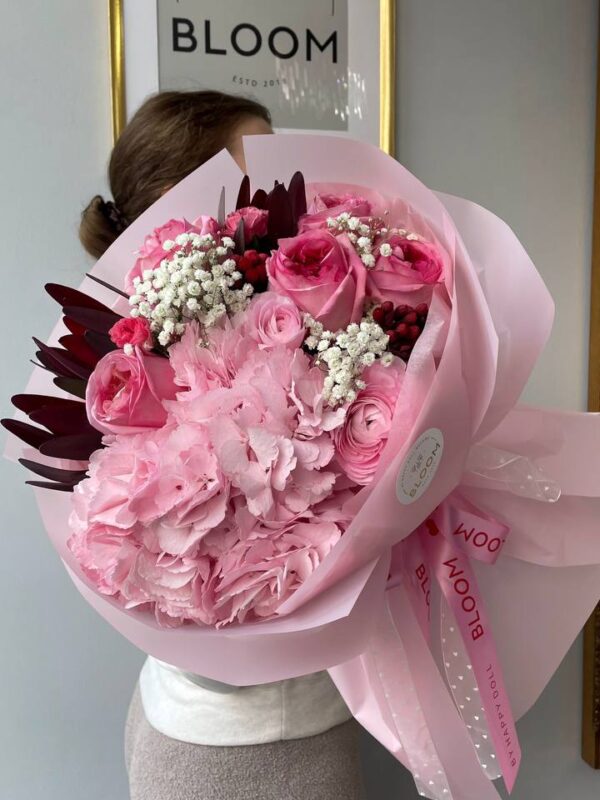 Авторські букети UA 21 Букет із білої гортензії та гіпсофіли в ніжній упаковці поруч із елегантно загорнутими подарунками з білими та золотими стрічками.