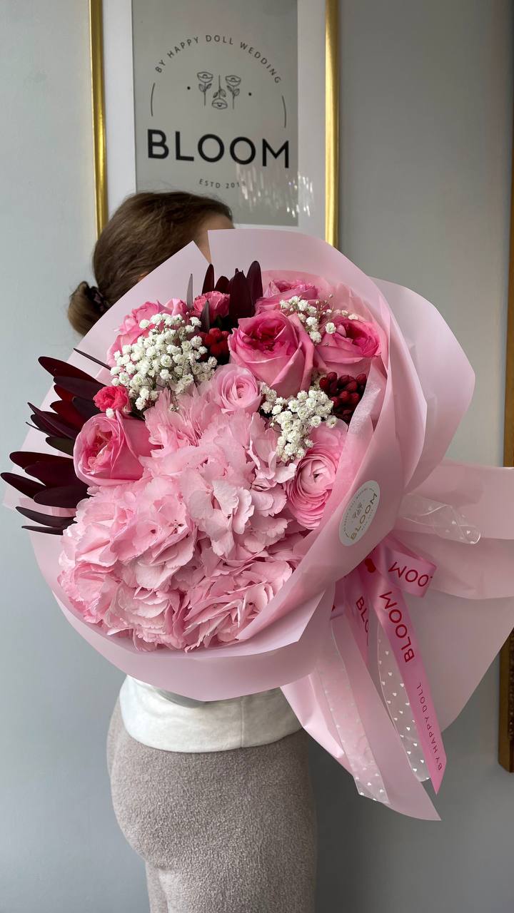 Pink melody / Рожева мелодія 1 Букет із білої гортензії та гіпсофіли в ніжній упаковці поруч із елегантно загорнутими подарунками з білими та золотими стрічками.