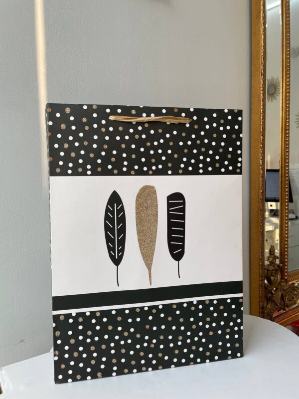 Чорний паперовий подарунковий пакет з білим і золотим пір’ям та дизайном у горошок