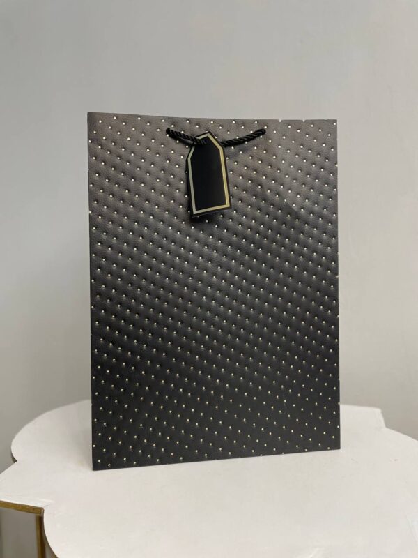 Чорний паперовий подарунковий пакет з золотим тисненням у вигляді точок та подарунковою біркою