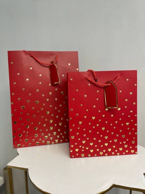 Червоний паперовий подарунковий пакет із золотими сердечками та подарунковою біркою