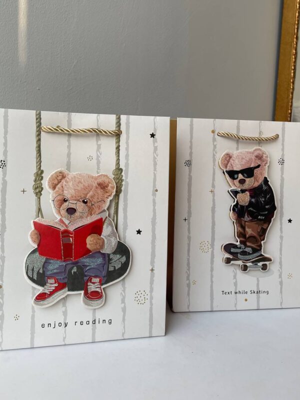 Паперовий подарунковий пакет з ведмедиком, що читає книгу, у світлому дизайні