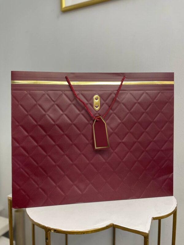 Бордовий паперовий подарунковий пакет з ромбоподібним тисненням, золотими деталями та крученими ручками