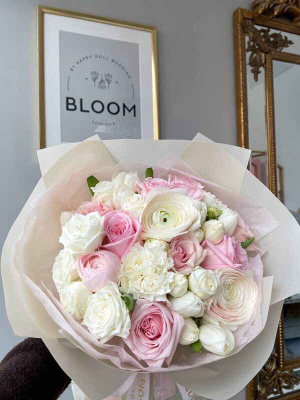 Пастельний букет з рожевих і білих квітів у фірмовому пакуванні Bloom.
