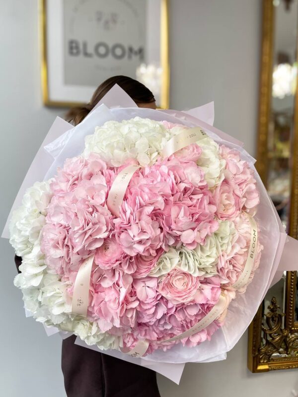 Ніжний об’ємний букет із рожевих і білих гортензій у світлій упаковці з брендованими стрічками Bloom
