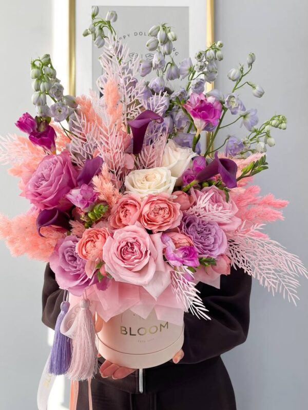 Квіткова композиція в коробці Bloom з трояндами, еустомою та каллами у рожево-лавандовій палітрі.