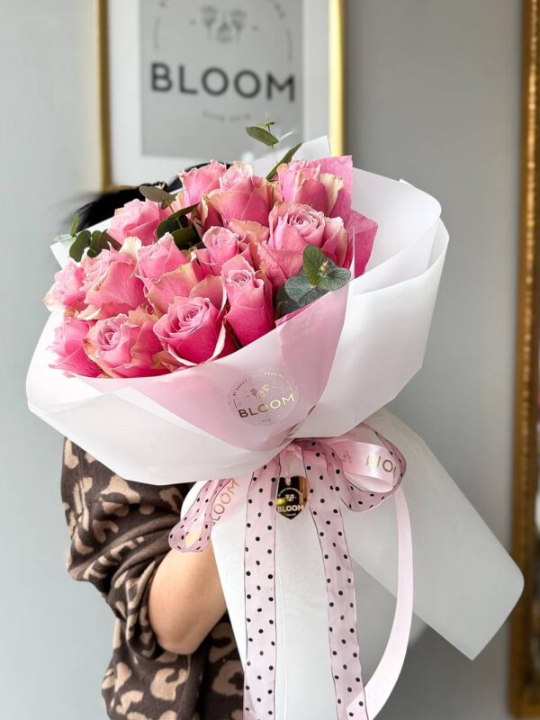 Букет з рожевих троянд у фірмовому пакуванні Bloom з рожевим бантом.