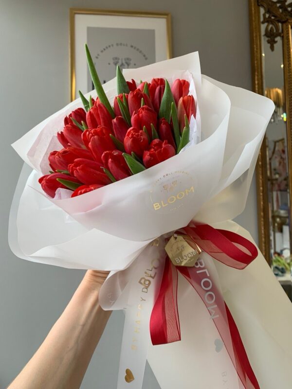 Букет із червоних тюльпанів у білій фірмовій упаковці Bloom з червоною стрічкою