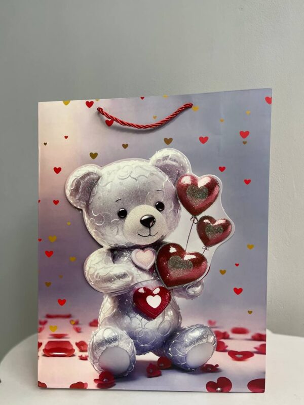 Паперовий подарунковий пакет зі срібним ведмедиком та червоними серцями на романтичному фоні