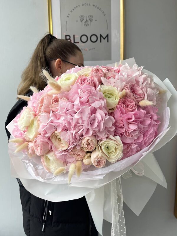 Великий ніжний букет з рожевою гортензією, ранункулюсами та садовими трояндами у білій упаковці Bloom.
