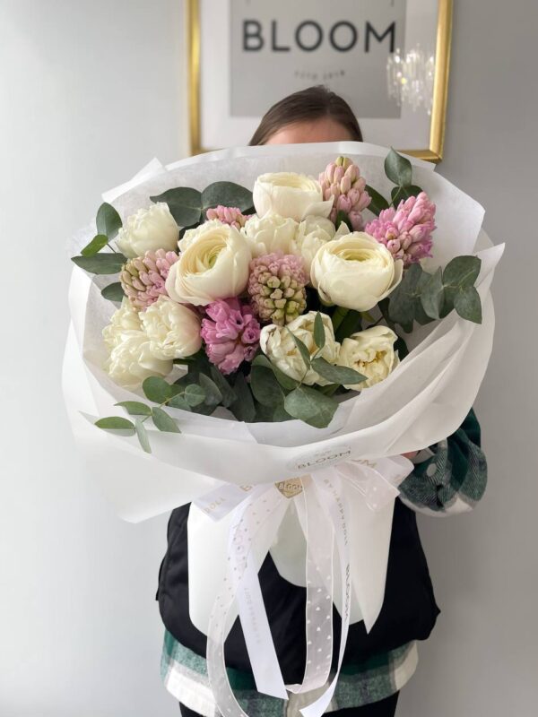 Ніжний букет квітів з білими ранункулюсами, рожевими гіацинтами та евкаліптом у білій упаковці Bloom.