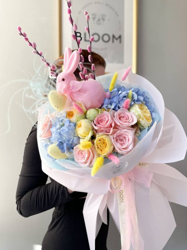 Святковий великодній букет з квітами та декоративним зайчиком у ніжних відтінках Bloom.