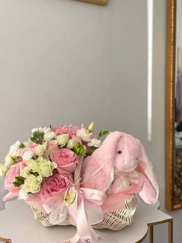 Квіткова композиція у білій корзині з рожевими та білими квітами і м’яким рожевим зайчиком від Bloom.