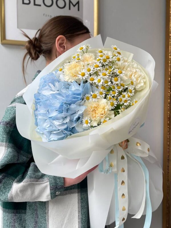Букет Bloom з блакитною гортензією, ромашкою та кремовими квітами у світлому оформленні.