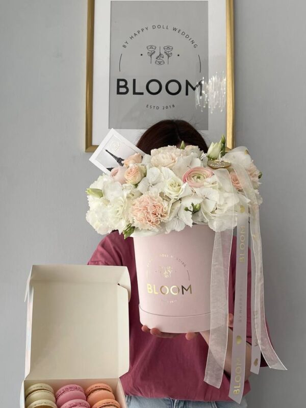 Квіткова композиція Bloom у рожевій коробці з білими квітами та набором макаронс.